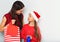 Happy mother speaking with her cute daughter in santa clause hat and present the Christmas gift in package