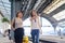 Happy mother and teenager daughter walking with suitcase at railway station