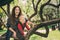 Happy mother and toddler son playing together outdoor and climbing apple tree