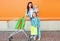 Happy mother and two children with trolley cart and shopping bag