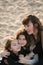 Happy mother with two daughters have fun on the beach at sunset.