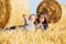 Happy mother and two year old girl next to hay bales in harvested field