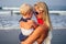 Happy mother in white dress with little daughter holding paper heart postcard on beach.beautiful blonde woman and her