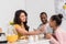 happy mother wiping face of little daughter after breakfast while father reading newspaper