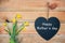 Happy mothers day card, wood planks with daffodils and a blackboard in shape of a heart