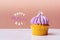 Happy Mothers Day, cute cupcake with small white heart on purple cream on pink background