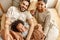 Happy multi ethnic family mom, dad and child  laughing, playing and tickles   in bed   at home