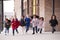 A happy multi-ethnic group of young school kids wearing coats and carrying schoolbags running in a walkway with their classmates o