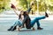 Happy multicultural couple sitting on a longboard on a street and rising hands