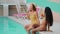 Happy multiethnic arabian and caucasian girl friends swing legs in water pool young female women students relax enjoy