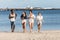 Happy multiethnic friends running along beach in summer
