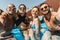 happy multiethnic friends in swimsuits and sunglasses posing