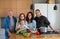 Happy multigeneration family indoors cooking at home, looking at camera.