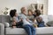 Happy multigenerational family enjoy playtime seated on sofa at home