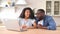 Happy multiracial couple using a laptop at home