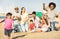 Happy multiracial families and children playing together with kite at beach vacation - Multicultural summer joy concept with