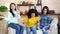 Happy multiracial girls having fun and dancing on sofa at home