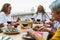 Happy multiracial senior friends having fun dining together on house patio