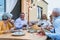 Happy multiracial senior friends having fun dining together on house patio