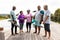 Happy multiracial senior friends holding exercise mats talking while standing on hardwood floor