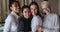 Happy multiracial women in formalwear standing indoor hugging and laughing