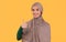 Happy Muslim Lady In Hijab Gesturing Thumbs-Up Over Yellow Background