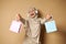 Happy Muslim woman in hijab with headphones listening to music and dancing with colored paper bags in her hands enjoying the