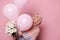 Happy Muslim woman in a pink hijab, experiencing happiness at a cute flower bouquet and helium balloons, pink background