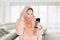 Happy muslim woman reading good news on cellphone