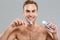 Happy naked young man cleaning teeth with toothbrush and toothpaste