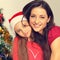 Happy natural smiling mother embrace her cute daughter in santa clause hat on Christmas green fur tree