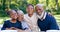 Happy, nature and grandparents with children at a picnic for family time and bonding in a garden. Smile, portrait and