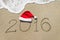 Happy new year 2016 with christmas hat on sandy beach