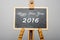 Happy New Year 2016 written on black chalkboard, easel painting