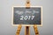 Happy New Year 2017 written on black chalkboard, easel painting