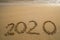 Happy New Year 2020 concept, 2020 number lettering on the sea beach, wave and golden light of sunset