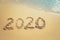 Happy New Year 2020 concept, 2020 number lettering on the sea beach, wave and golden light of sunset