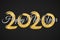 Happy New Year 2020. Numbers of golden glitters with calligraphy on a black background. Grunge brush. Golden confetti. Vector