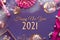 Happy New Year 2021 gilded text in frame with New Year party table setup. Flat lay in golden, pink and purple on linen textile