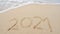 Happy New Year 2021 Text on the beach, 2021 year message hand written in sand on beautiful beach Waves crashing on sandy shore