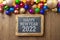 Happy New Year 2022 greeting card with modern  balls decoration on wooden background