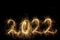 Happy New Year 2022. Number 2022 written sparkling sparklers isolated on black background with copy space for text.