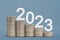 Happy New Year 2023. Financial theme, stacks of coins stacked in ascending order, like a graph, on a blue background