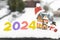 Happy New Year 2024 - numbers in snow, souvenir figurines of a snowman, a cozy cottage, a Santa ha