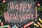 Happy New Year - background or a postcard. Happy new year lettering chalk on a school board. Gift mock-up board decorated with fir