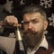 Happy New Year. Christmas man with beard on serious face open champagne.