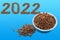 Happy new year for pets. Date 2022 composed of dry food and a round metal bowl full of crunchy dry food for dogs or cats