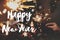 Happy New Year text on hands holding burning sparklers on background of christmas tree in lights. Season`s greetings card.