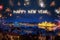 Happy New Year written with sparkle fireworks on night sky above Budapest surrounded by lots of fireworks