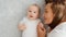 Happy newborn baby with his mother. Healthy newborn baby in a white t-shirt with mom. Closeup Faces of the mother and infant baby